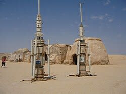 Two large metal towers stand in a desert.