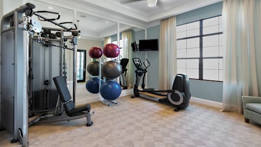 A home gym with a variety of equipment including a leg press machine, a rowing machine, and a bench press.