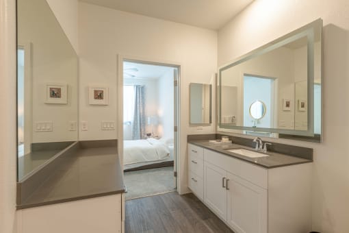 a ensuite bathroom with a large mirror and white cabinets