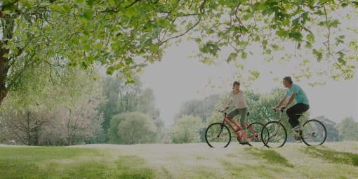 a man and a woman riding bikes in a park