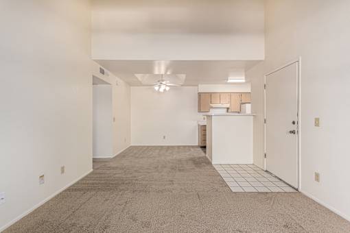 A spacious room with a carpeted floor and a ceiling fan.