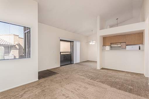 A spacious room with a carpeted floor and a window with blinds.