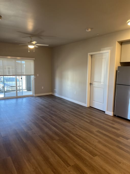 an empty living room with wood floors and a refrigerator
