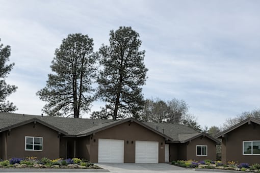 A row of houses with brown roofs and white garage doors.