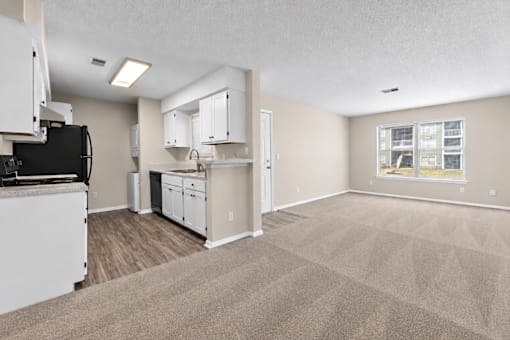 A kitchen with white cabinets and a black fridge is shown.