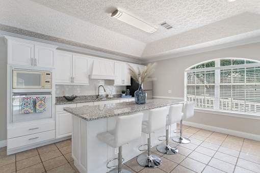 a kitchen with white cabinets and a marble counter top