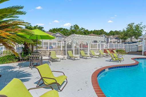 a pool with chairs and umbrellas next to a pool