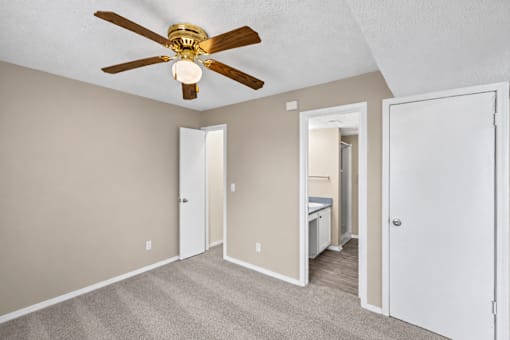 A room with a ceiling fan and carpeted floor.