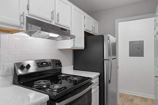 a kitchen with white cabinets and black appliances and a refrigerator