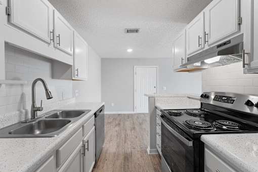 a kitchen with white cabinets and a stove and sink