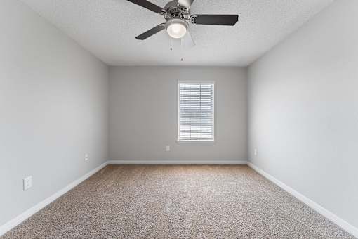 an empty room with a ceiling fan and a window