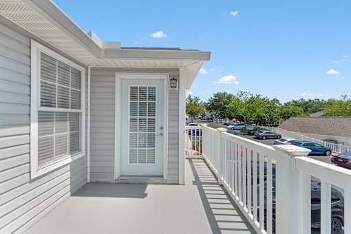 a balcony with white railing and a door into a home