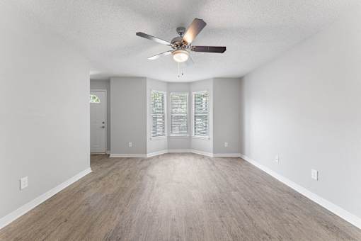 an empty living room with a ceiling fan