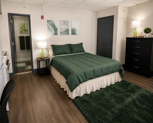 A bedroom with a bed, nightstand, and chair.