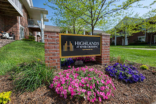 A sign for Highlands at River Crossing is in front of a building.