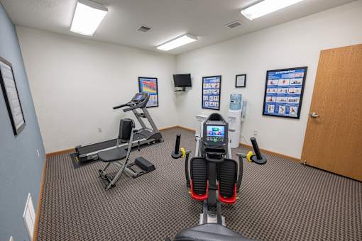 A gym room with a treadmill, exercise bike, and other equipment.