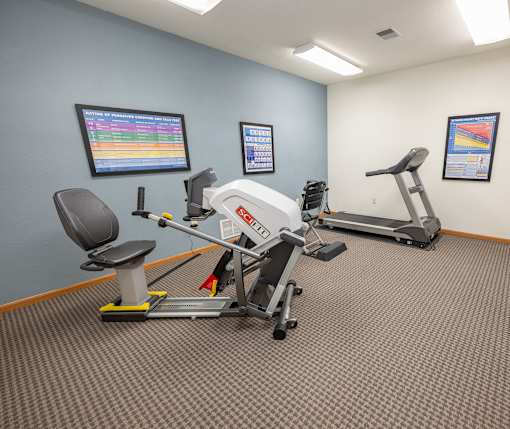 A gym room with a treadmill, exercise bike, and other equipment.