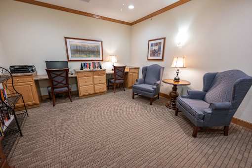 A room with a carpeted floor and a variety of chairs and tables.