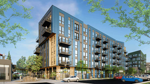A modern apartment building with balconies and cars parked in front.