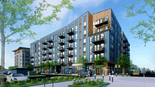 A modern apartment building with balconies and a green landscape in the foreground.