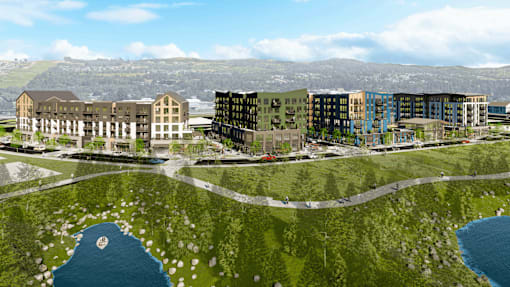 A modern building complex is surrounded by a grassy area and a body of water.