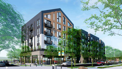 A modern multi-story building with balconies and a green wall on the side.