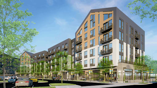 A modern apartment building with a green tree in front.