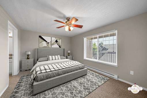 A bedroom with a large bed and a ceiling fan.
