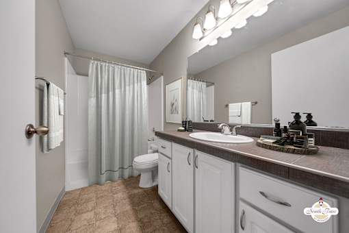 A bathroom with a toilet, sink, and shower curtain.