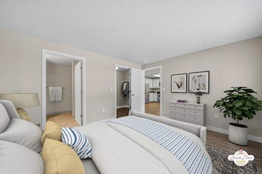 A bedroom with a large bed and a potted plant.