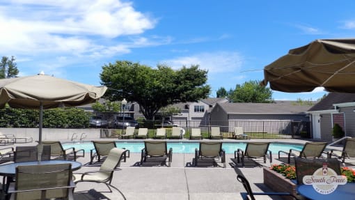 a swimming pool with chairs and umbrellas on a patio