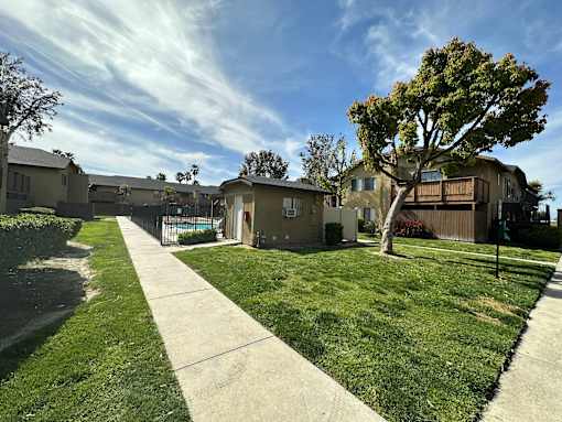 Buildings and landscaping around gated swimming pool at Riverdale Apartment Homes in Hemet, California.
