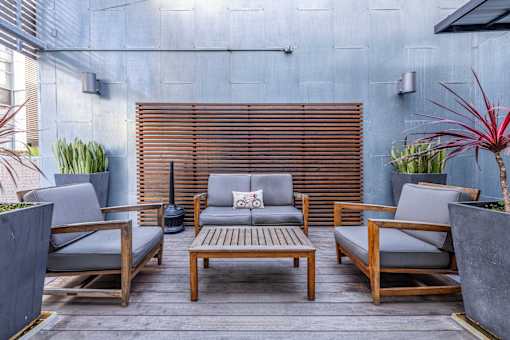 A patio with wooden furniture and a grey cushion.