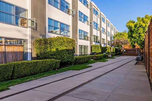 A long concrete walkway leads between two rows of apartment buildings.