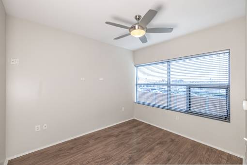 A room with a ceiling fan and a window with blinds.