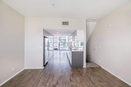 A room with a wooden floor and a staircase leading to another room.