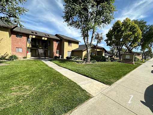 Sidewalk view of lawn and gardens at Riverdale Apartment Homes in Hemet, California.