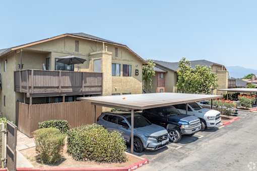 A carport with several cars parked in front of a house.