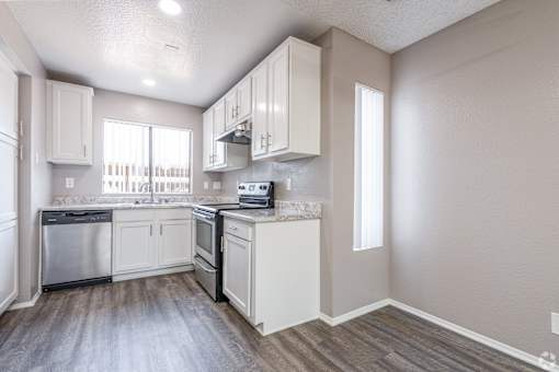 A kitchen with white cabinets and a wooden floor.