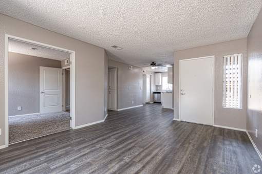 A spacious room with wood flooring and white walls.