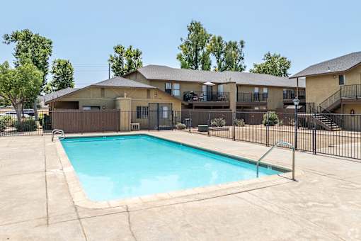 A swimming pool in a backyard surrounded by a fence.