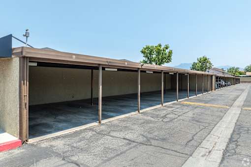 A parking lot with a concrete building and a tree in the background.