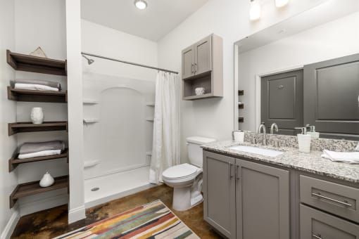a bathroom with gray cabinets and white walls