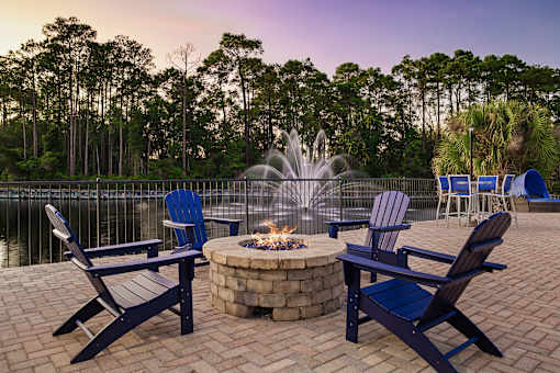 A fire pit surrounded by chairs in a backyard setting.