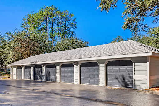A large garage with multiple doors is surrounded by trees.