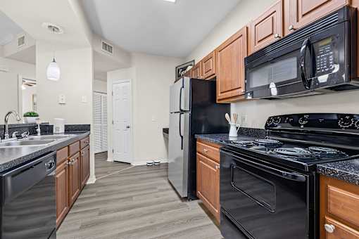 A kitchen with black appliances and wooden cabinets.