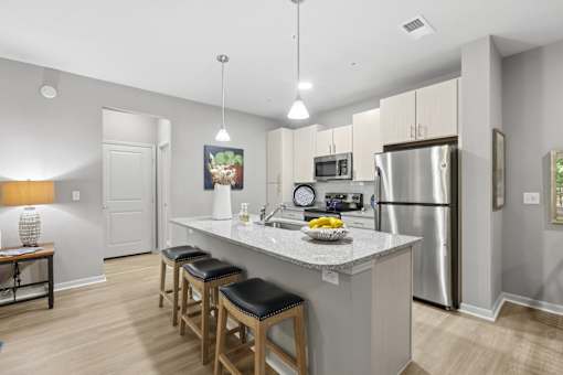 A kitchen with a refrigerator, microwave, and stove top oven.