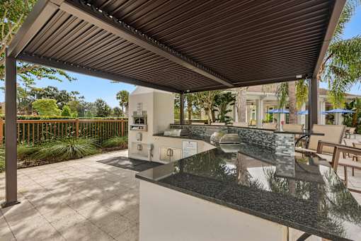 A modern outdoor kitchen area with a barbecue grill and a sink.