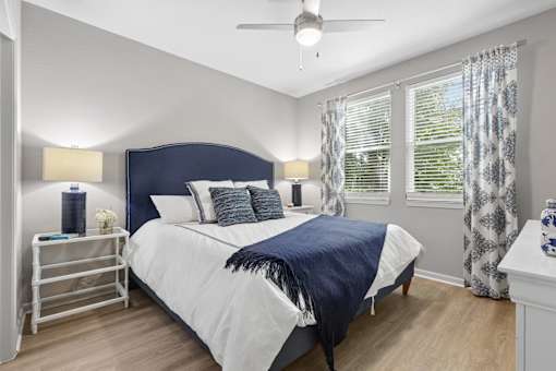 A bedroom with a bed, nightstand, and window.