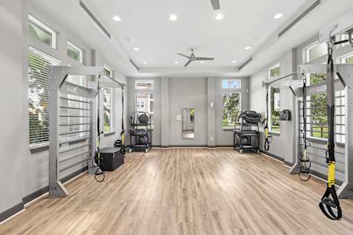 A spacious gym with a variety of equipment and a ceiling fan.